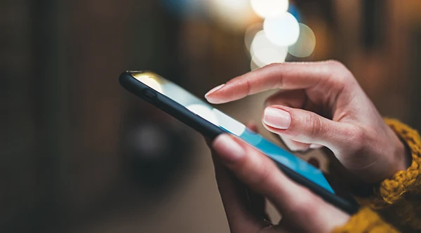 Close up of slender Black hands scrolling through a smart phone at Rolling Plains Dentistry in Quanah, TX